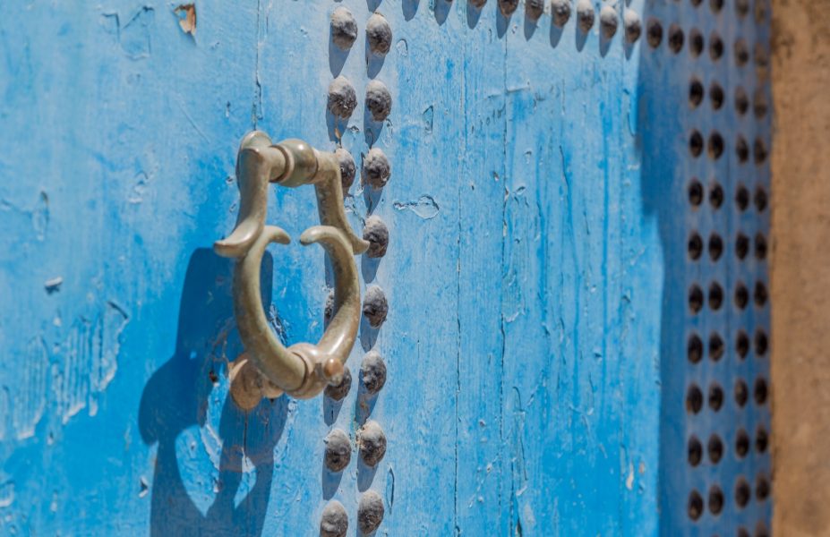 grey door knocker on blue wooden door with rivets